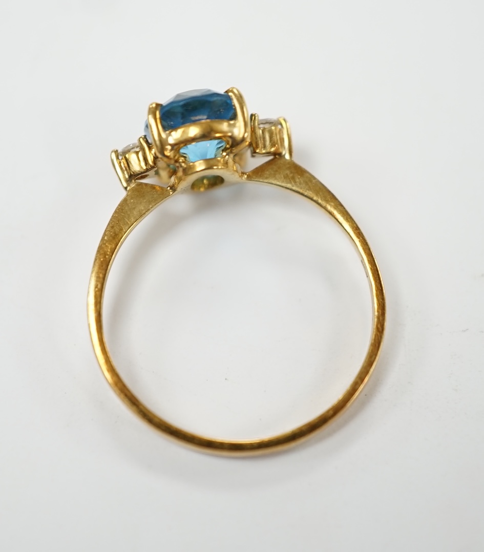 A 750 yellow metal and single stone oval cut blue topaz and two stone diamond set ring, size M/N, gross weight 2.5 grams. Good condition.